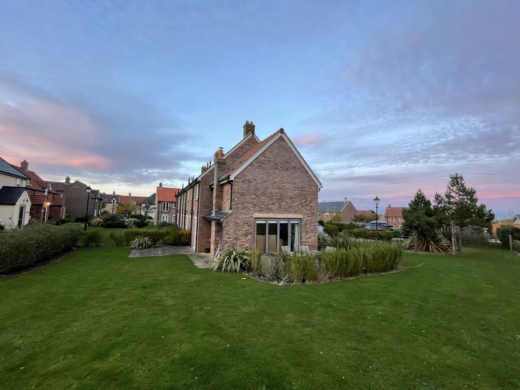 Caramel Cottage and its lawn at dusk, on the corner plot at The Bay, Filey