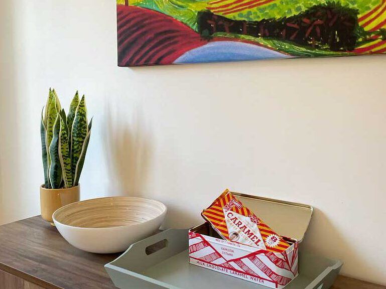 A bowl and a box of caramels on the sideboard at Caramel Cottage, below a framed print