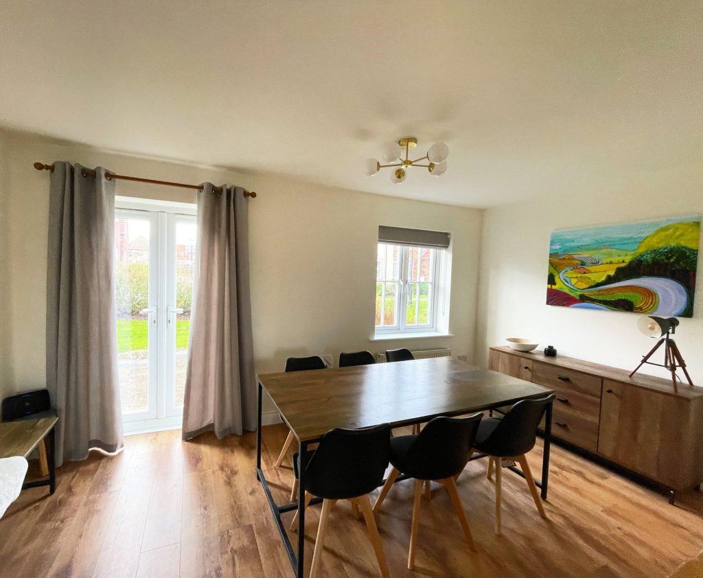 A wider view of the dining room at Caramel Cottage, with the table for six and the kitchen beyond