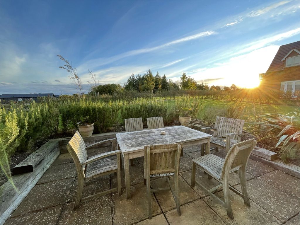 The garden table and chairs at Caramel Cottage at sunset, looking over the meadow