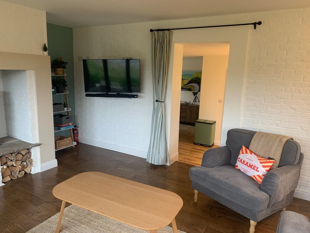 The separate living room at Caramel Cottage with sofa, armchair and wall-mounted television