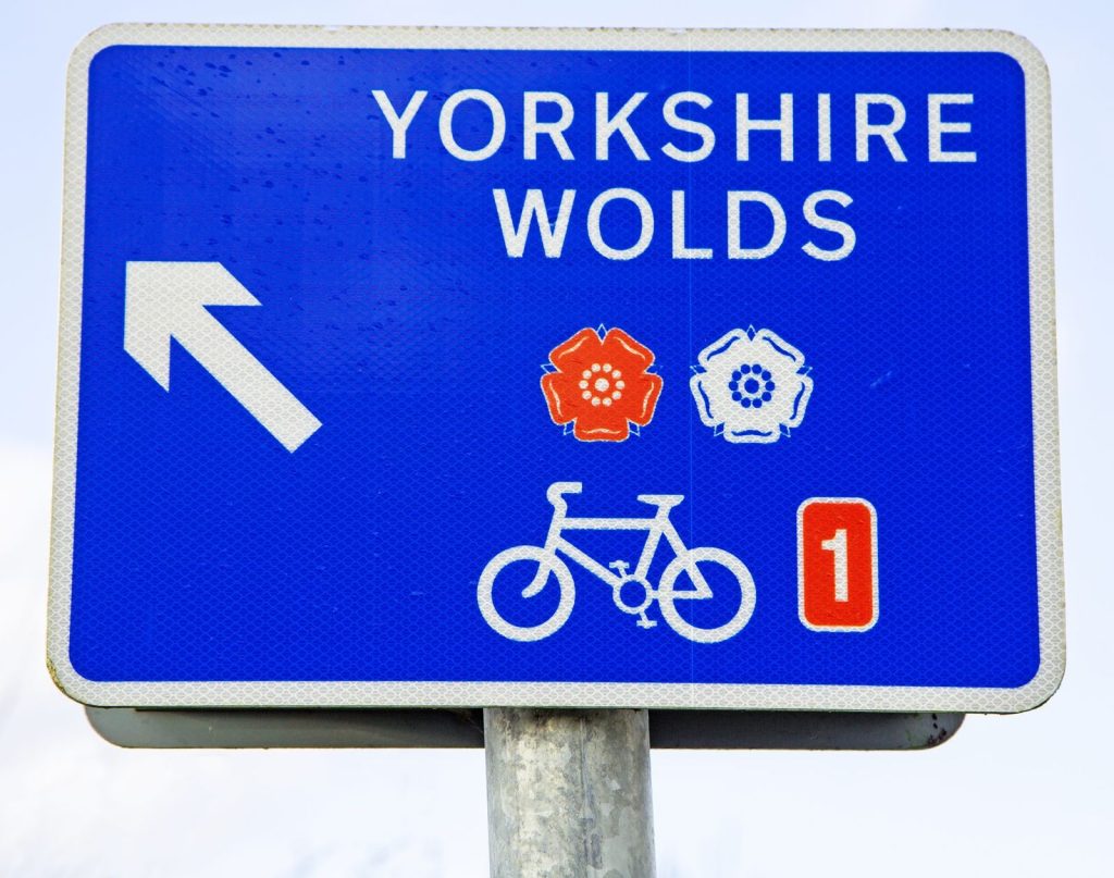 A blue Yorkshire Wolds cycle route sign carrying the National Cycle Network number 1